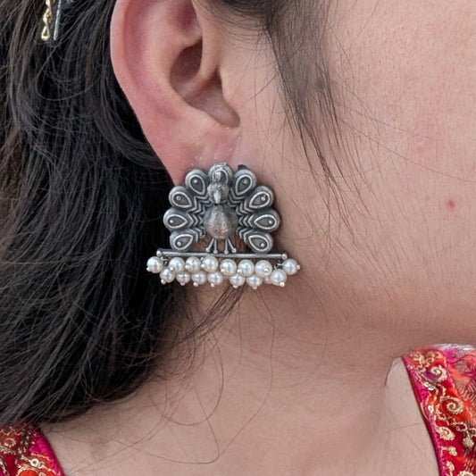 Close-up of an ornate earring worn by a person with a colorful garment.